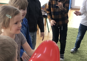 Dzieci przekazują sobie balonowe serduszko